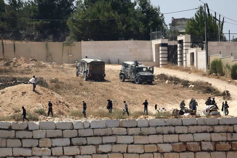 Israeli soldiers standing guard next to settlers outside Palestinian homes in Qusra village, West Bank