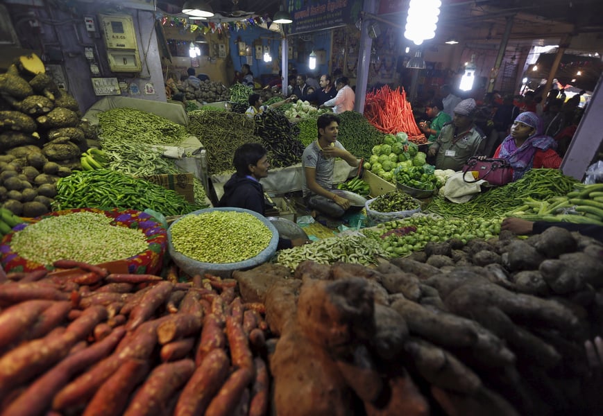 Shoppers buy vegetables at a market stall in Ahmedabad as India's retail inflation stays above target