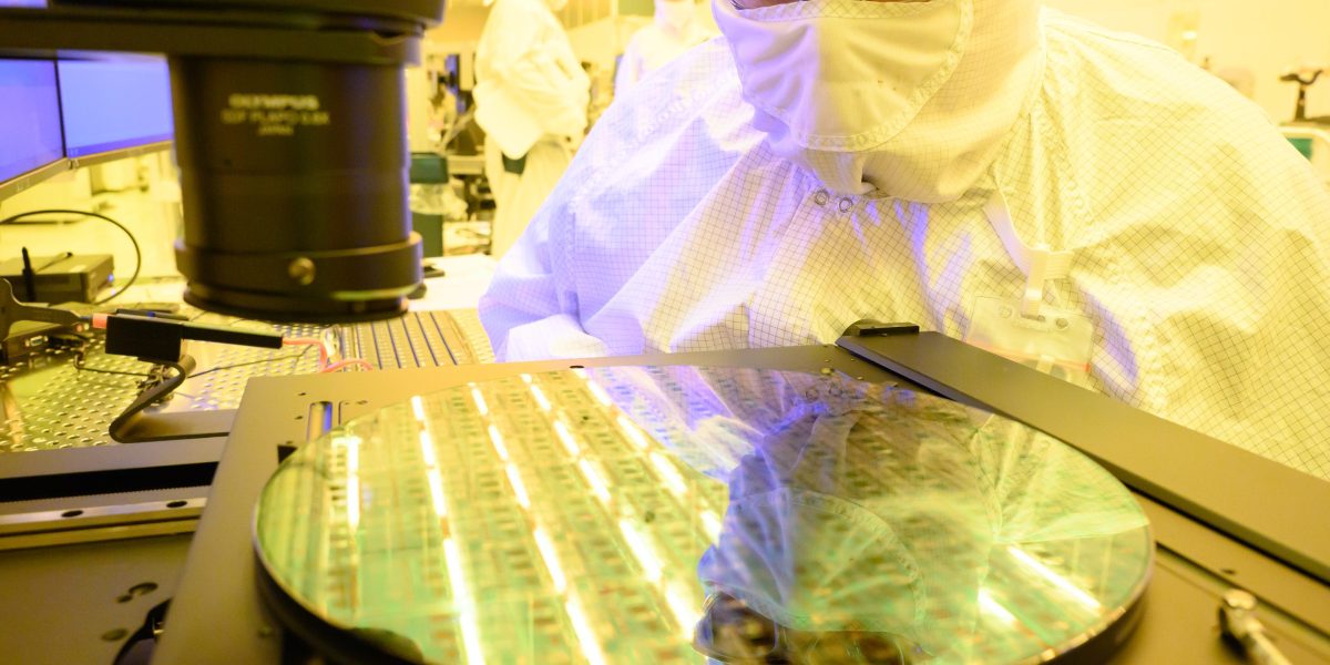 INTC stock today: a technician in cleanroom coveralls inspects a silicon wafer at an Intel fabrication plant