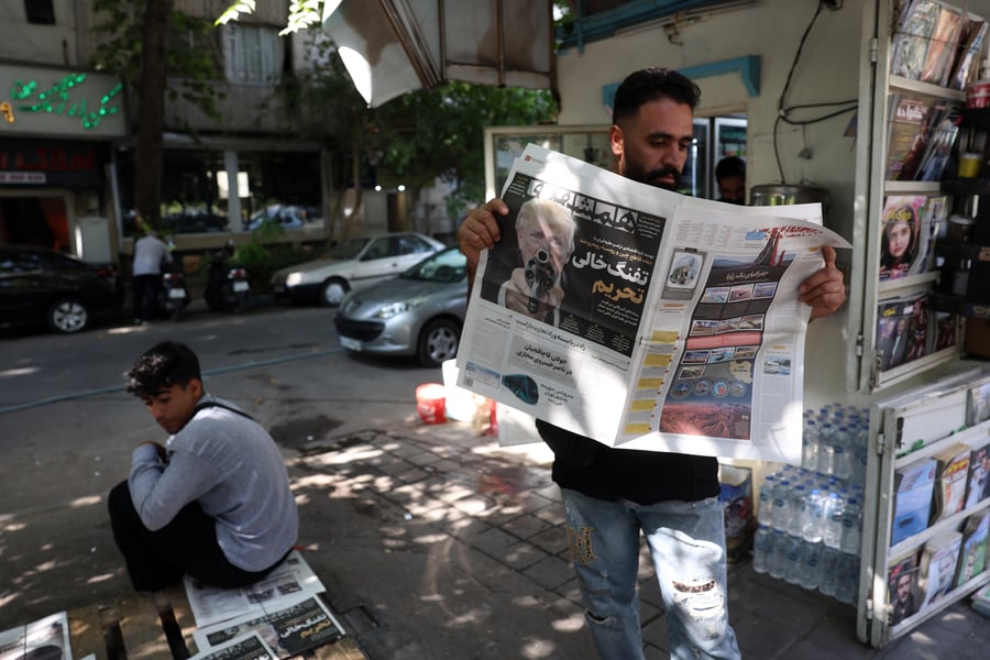 Iranian man reads newspaper with headlines about US Iran economic sanctions standoff August 2026