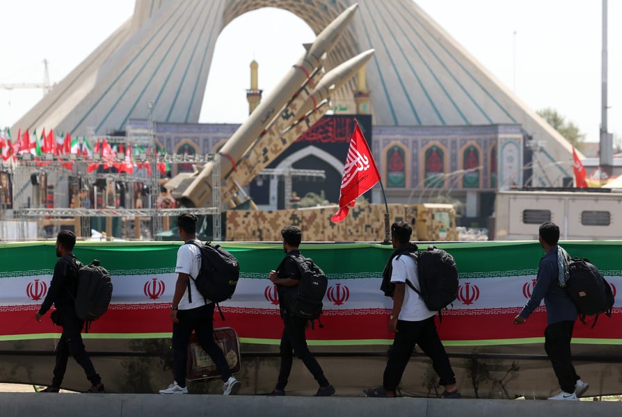 People walk past Iranian missiles as the United States launches Operation Economic Outcast sanctions targeting Iranian entities