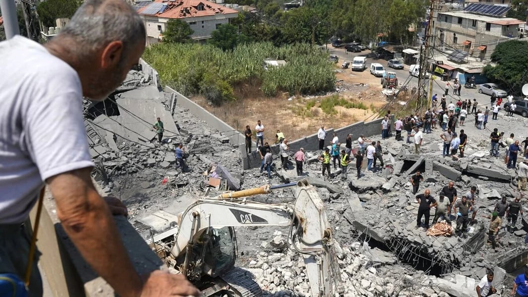 Rescue workers and residents search the site of an Israeli air strike in Deir al-Zahrani, southern Lebanon, August 2026