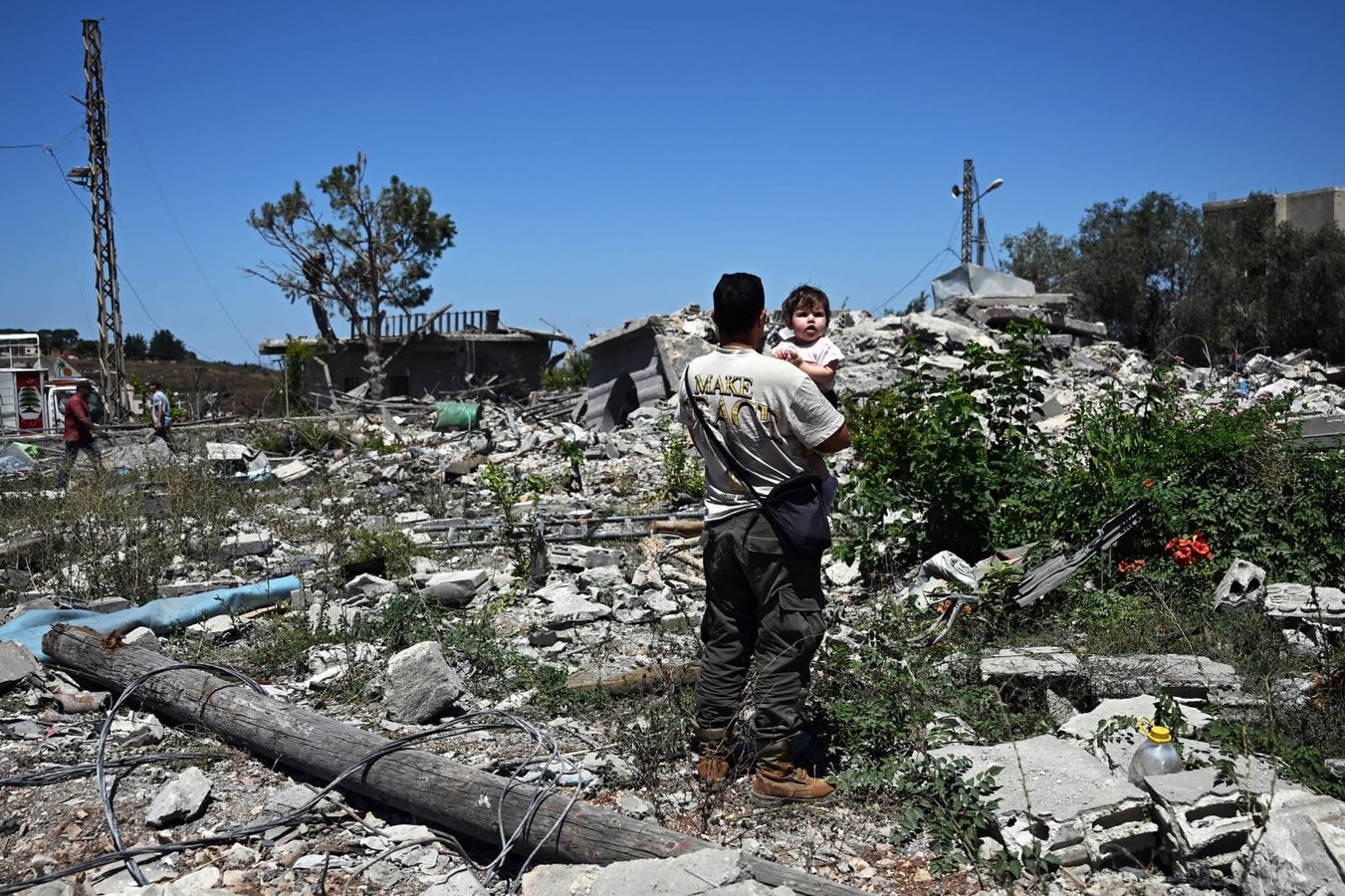 A man carries a young girl through the ruins of a destroyed home in Zawtar al-Gharbiyah southern Lebanon