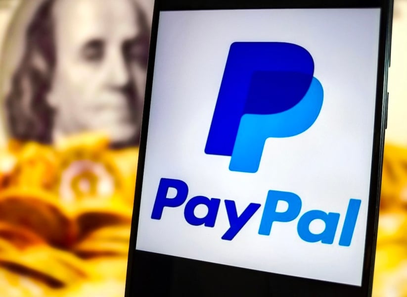 PayPal app logo on a smartphone against a background of US currency, representing the company's digital payments business and $53 billion acquisition talks with Stripe