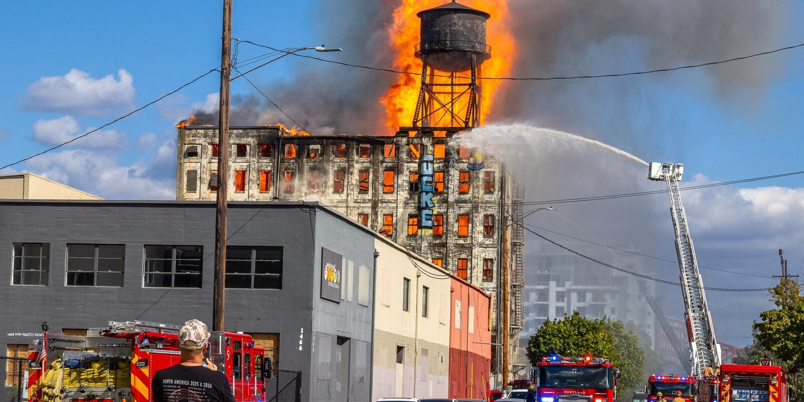 Massive flames engulf Centennial Mills warehouse on NW Naito Parkway in Portland as fire trucks and aerial ladders battle the four-alarm blaze