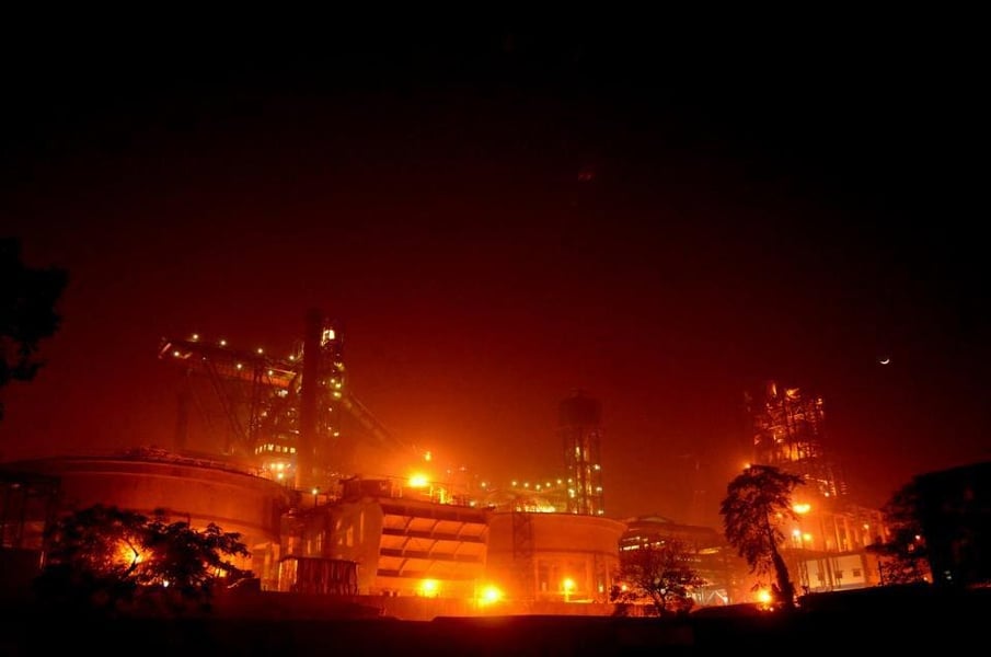 An Indian integrated steel works lit up at night, the kind of continuous-process plant that gives steel producers high operating leverage