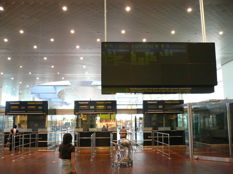 Passengers at border control booths in a Schengen airport terminal