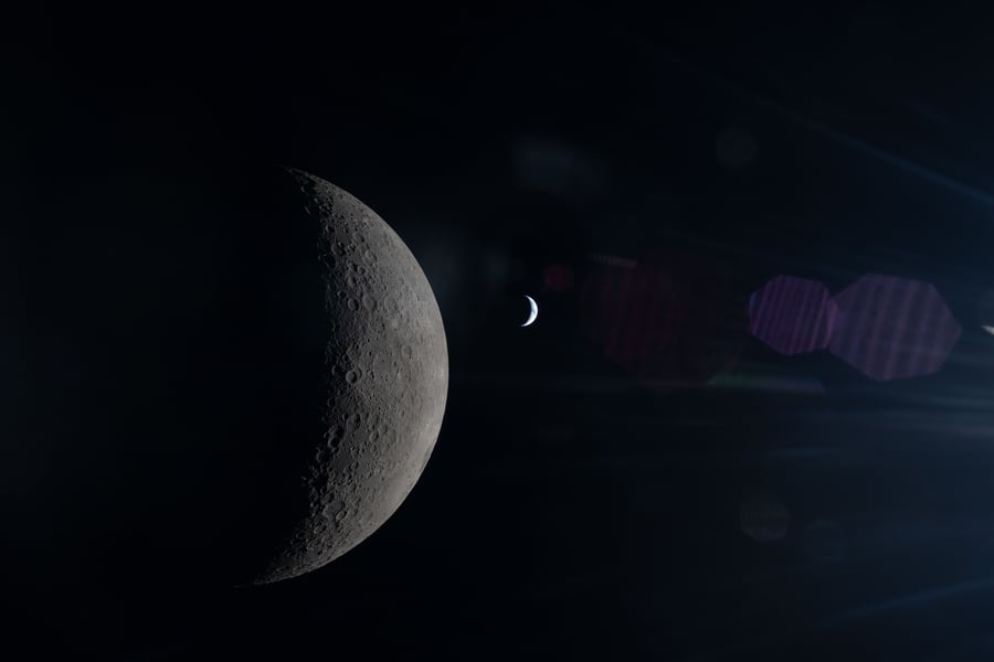 The Moon in sharp detail in the foreground with Earth small and softly lit in the background, both partially illuminated by the Sun