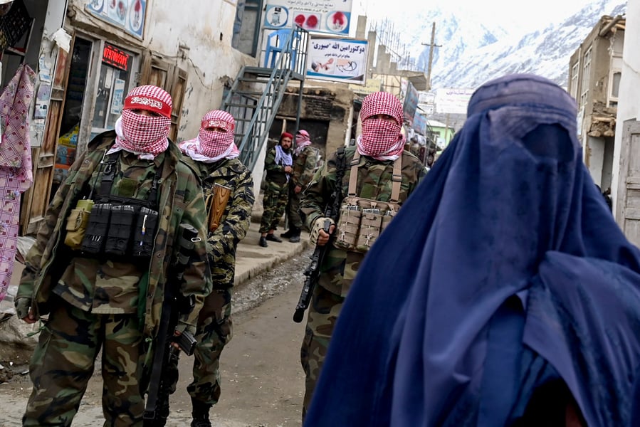 Taliban security guard standing beside a burqa-clad woman in Afghanistan