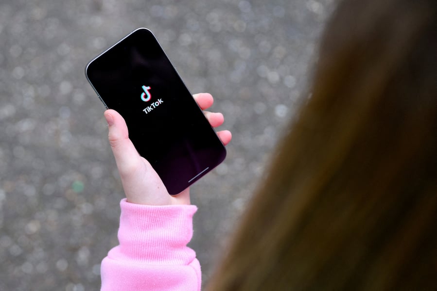 A teenager looks at TikTok on a smartphone, representing the platform's COPPA violations affecting children under 13