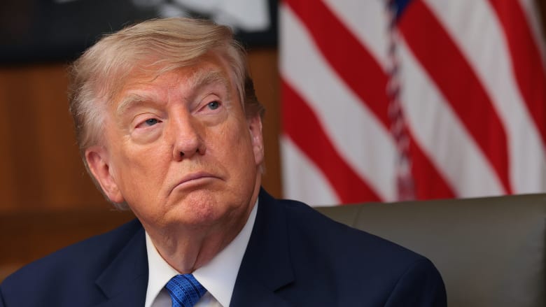 US President Donald Trump seated with American flag in background