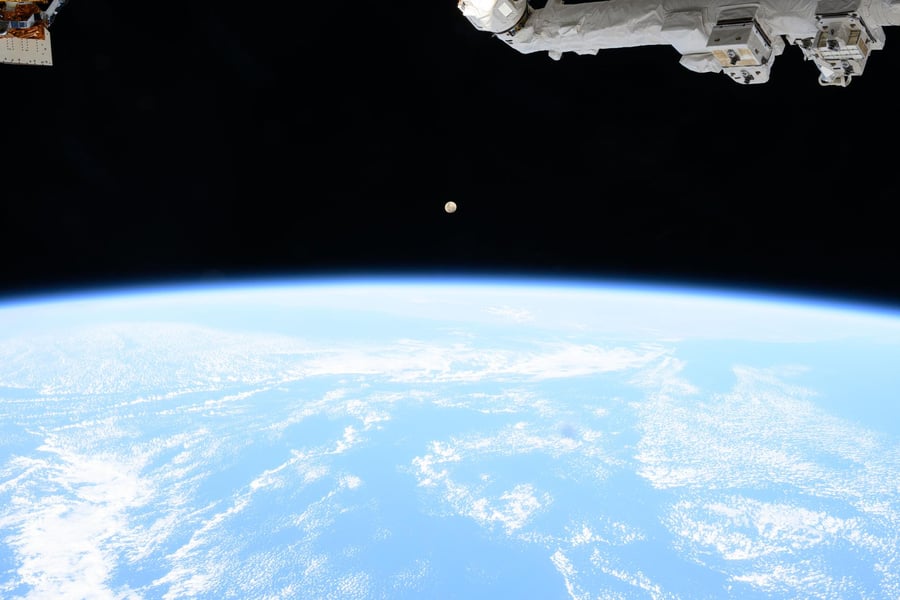 A waxing gibbous moon hangs above the bright curve of Earth's atmosphere in a photograph taken from the International Space Station
