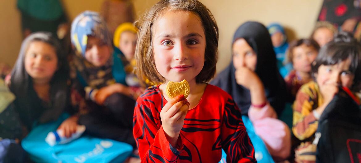 A young girl in Afghanistan consuming WFP-provided nutritional biscuits in Zabul Province