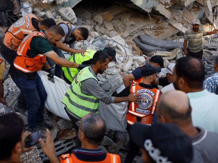 Rescue workers search through rubble of the collapsed al-Saada building in Gaza City after 21 people including 12 children were killed