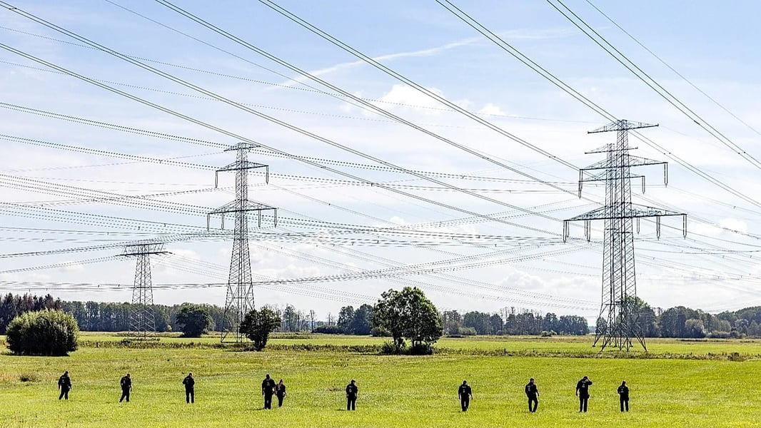 German police officers search field under high-voltage power lines after substation attack near Preilack Brandenburg September 2026