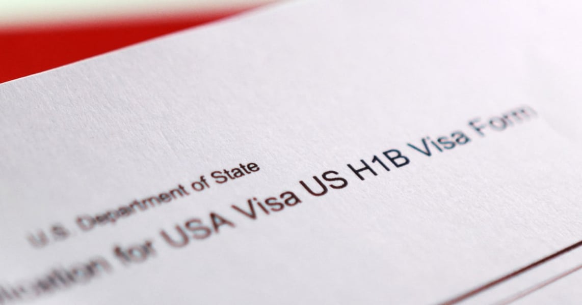 H-1B visa application form on desk with pen