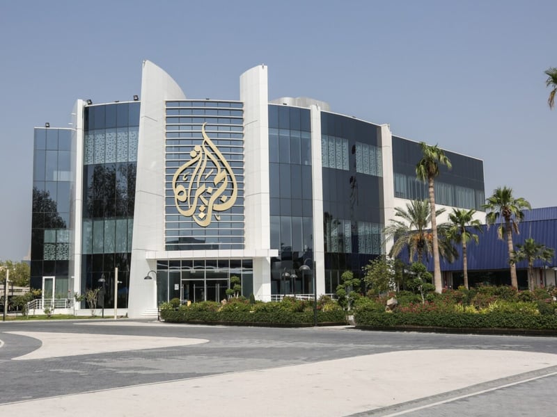 The glass-fronted Al Jazeera building with the network's gold calligraphic logo on its facade