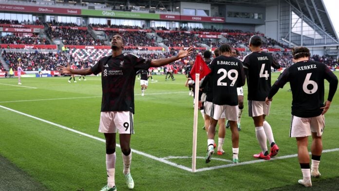 Liverpool striker Alexander Isak, wearing number 9, celebrates by the corner flag at the Gtech Community Stadium as team-mates run towards him