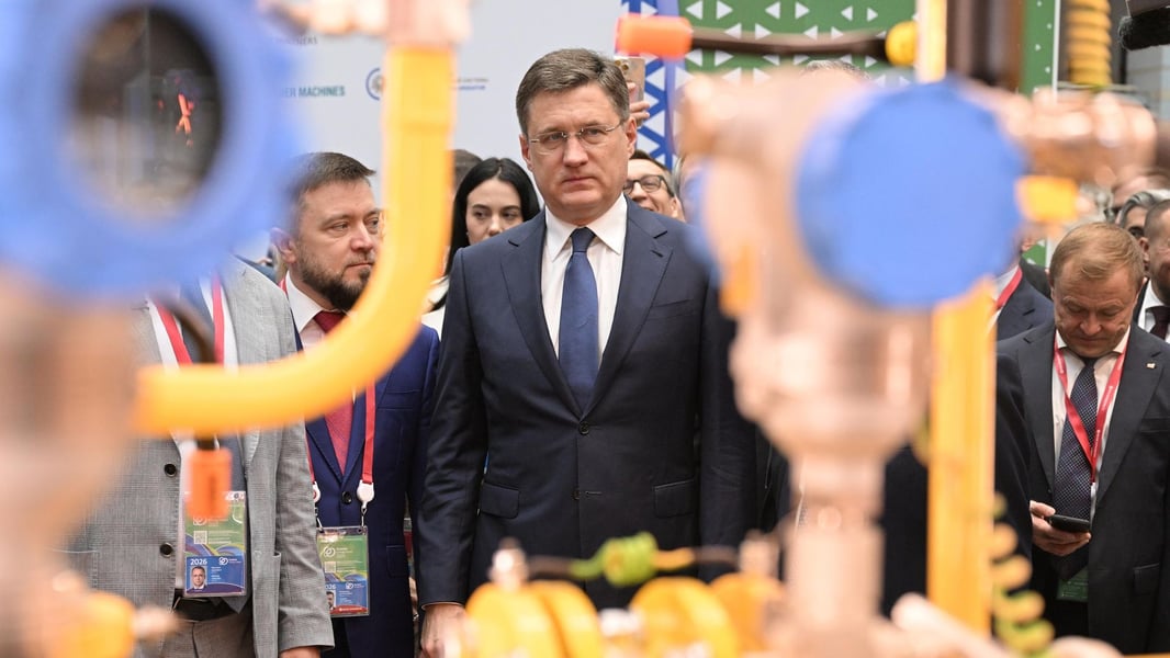 Russia's Deputy Prime Minister Alexander Novak at the Russian Energy Week 2026 forum, standing among attendees with blurred pipe fittings in the foreground