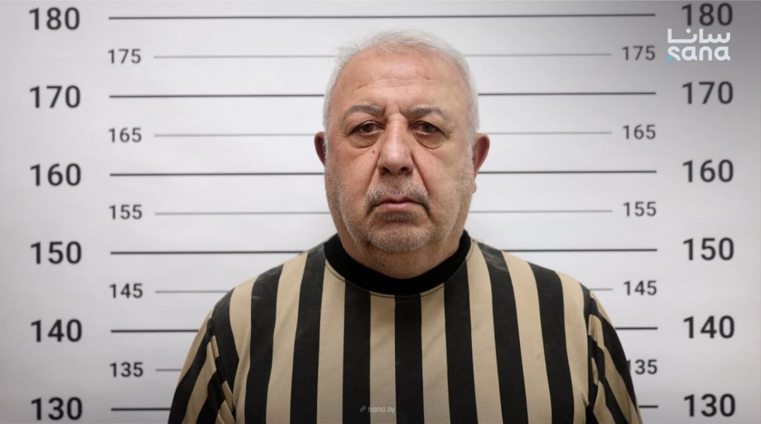 Ali Kayali, also known as Mihrac Ural, photographed against a height chart in a photo published by SANA with its report of his arrest