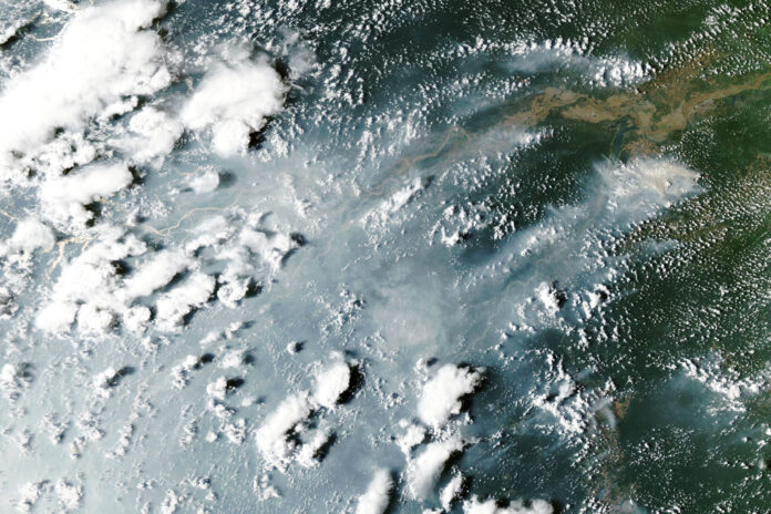 Satellite view of grey smoke plumes streaming across the Amazon River and rainforest from fires near Manaus and Santarem on October 12, 2026