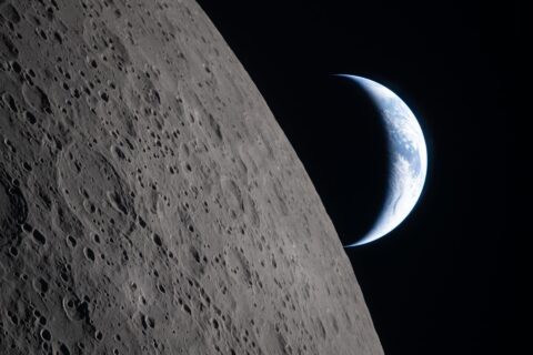 A crescent Earth sets behind the edge of the cratered Moon in a photograph taken by the Artemis II crew