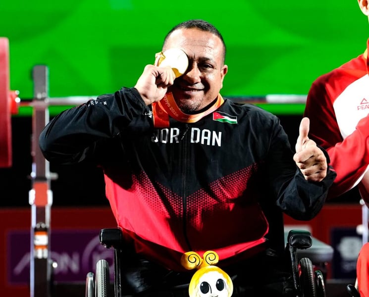 Jordan's Omar Qarada holds his gold medal to one eye after winning the men's up to 49kg Para powerlifting title at the Aichi-Nagoya 2026 Asian Para Games
