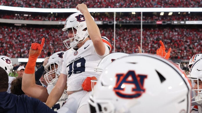 Auburn players in white helmets celebrate on the field at Sanford Stadium after beating No. 1 Georgia