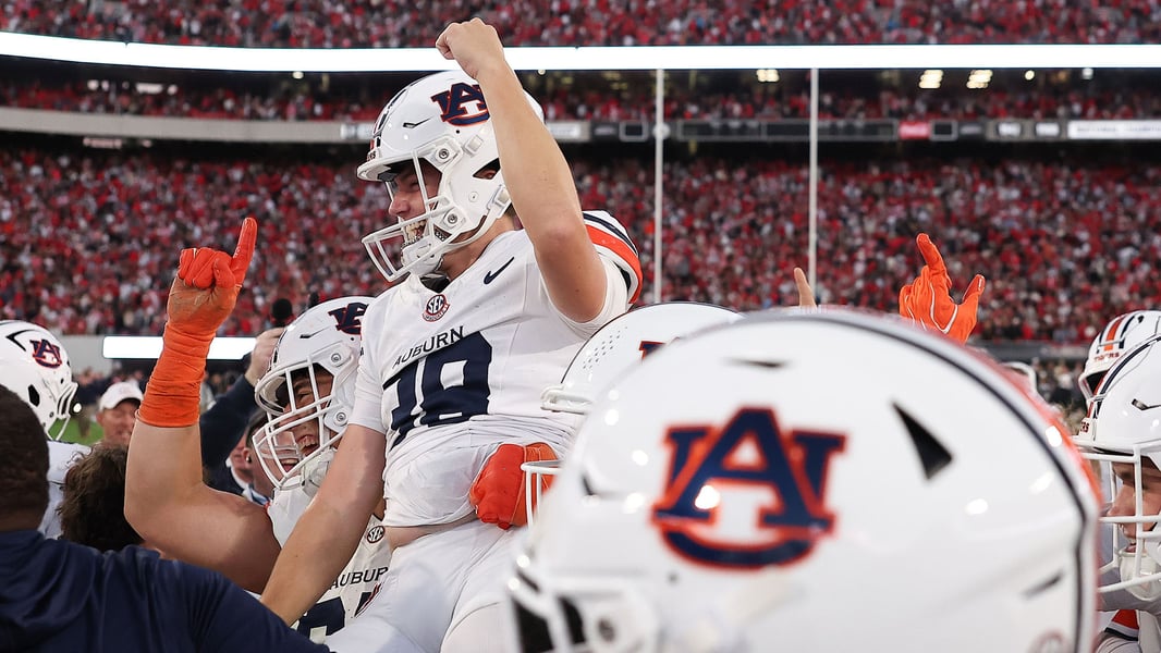 Auburn players in white helmets celebrate on the field at Sanford Stadium after beating No. 1 Georgia