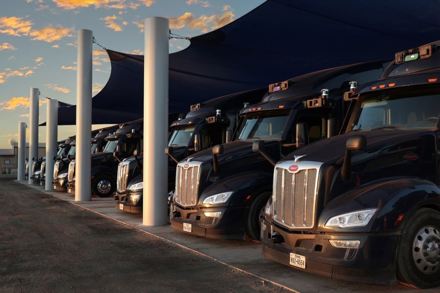 Aurora trucks parked under a canopy at a terminal