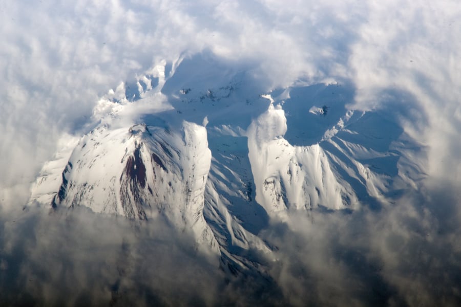 Snow-covered summit of Avachinsky volcano on Russia's Kamchatka Peninsula rising through a ring of cloud, seen from orbit