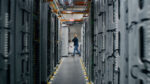 A technician in a corridor between server racks inside an Amazon Web Services data center in eastern Oregon