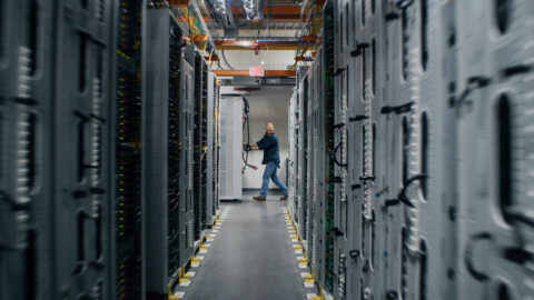 A technician in a corridor between server racks inside an Amazon Web Services data center in eastern Oregon