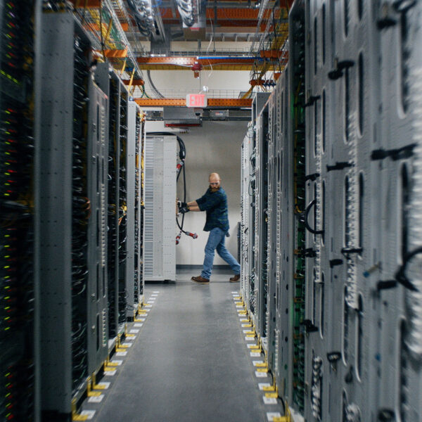 A technician in a corridor between server racks inside an Amazon Web Services data center in eastern Oregon