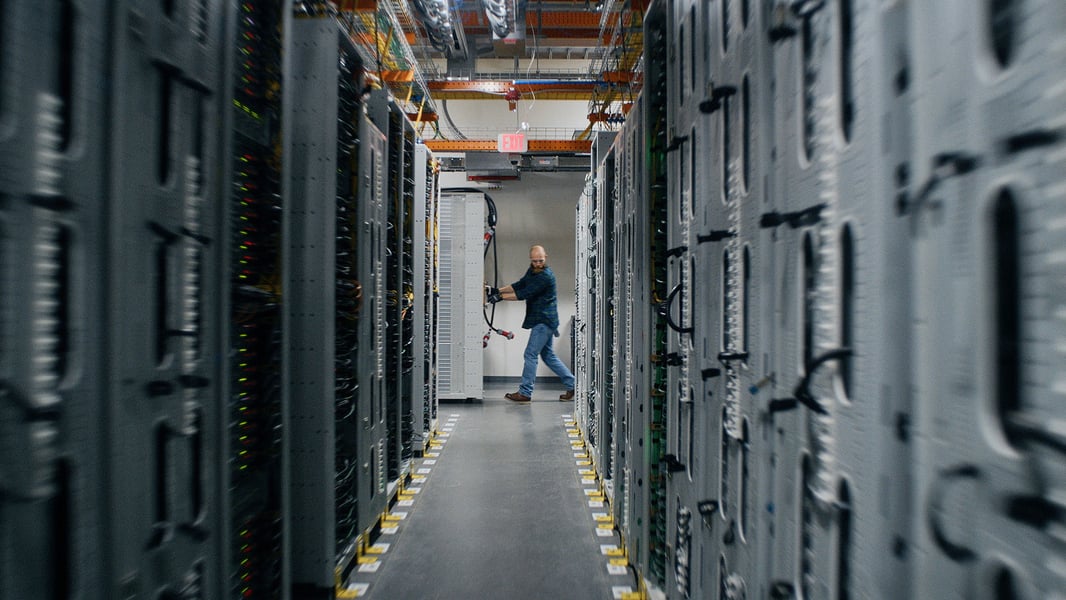 A technician in a corridor between server racks inside an Amazon Web Services data center in eastern Oregon
