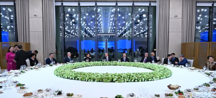 Guests seated around a large round table with a floral centerpiece at a dinner in Baku for participants of the CICA summit