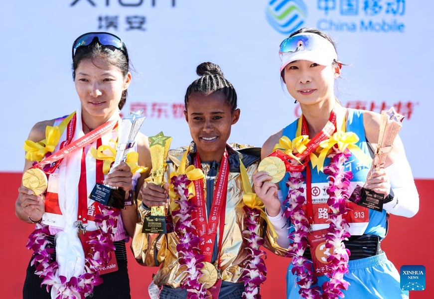 Anchinalu Dessie Genaneh of Ethiopia between China's Cirencuomu and Lu Ying, holding trophies and medals on the women's marathon podium