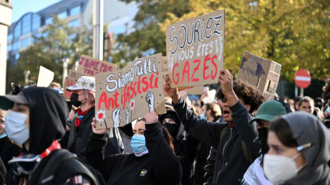 Young masked protesters hold up hand-made cardboard signs in French and Italian at a demonstration reported from Belgium