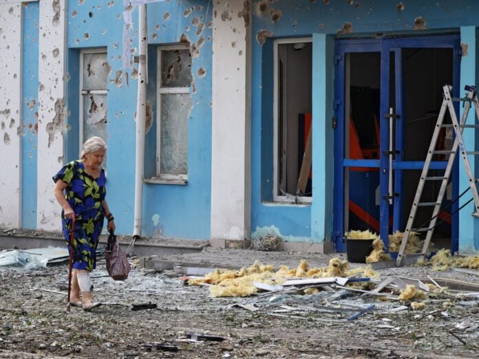 A woman walks past a bank damaged during an overnight Ukrainian drone attack in Belgorod, Russia