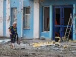 A woman walks past a bank damaged during an overnight drone attack in Belgorod, Russia