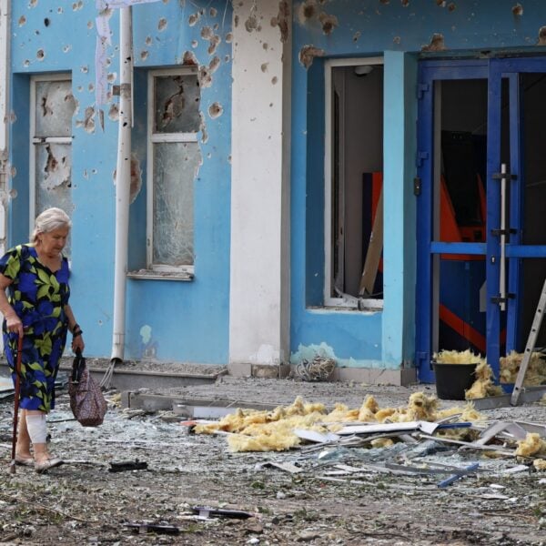 A woman walks past a bank damaged during an overnight drone attack in Belgorod, Russia