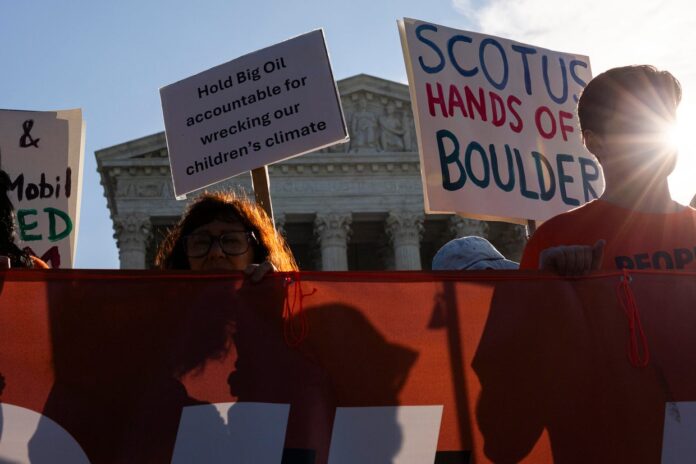 Demonstrators hold signs reading Hold Big Oil accountable and SCOTUS hands off Boulder outside the US Supreme Court