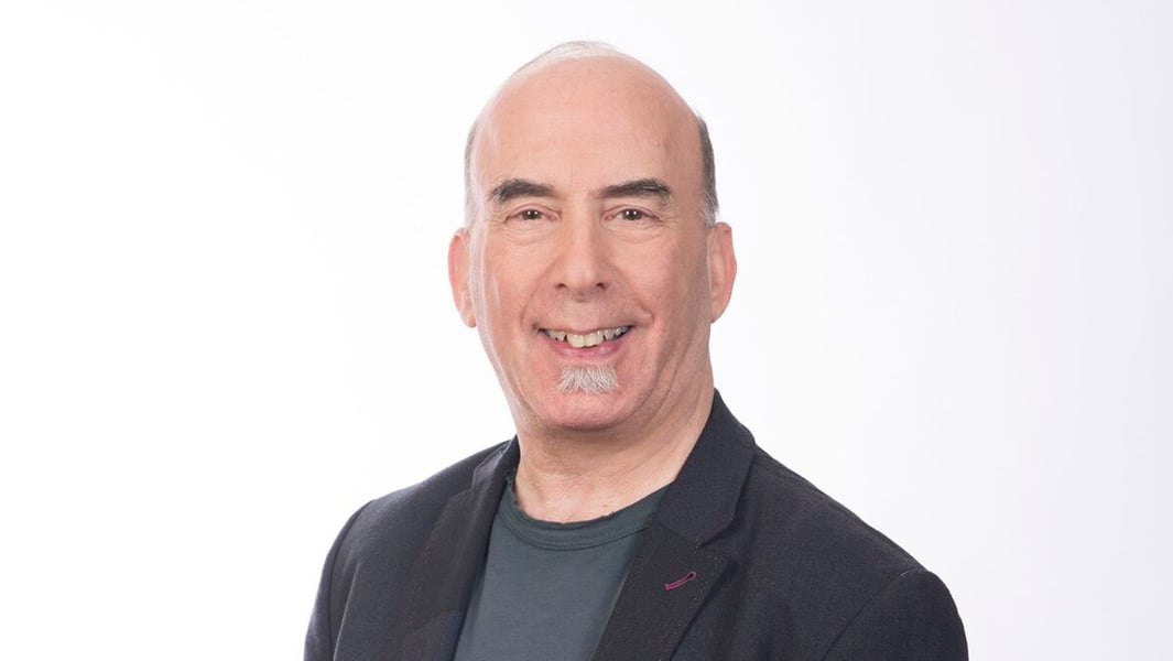 Portrait of television writer and producer Bruce Helford smiling against a white backdrop