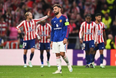 Manchester United captain Bruno Fernandes walks with his head down as Atletico Madrid players celebrate behind him