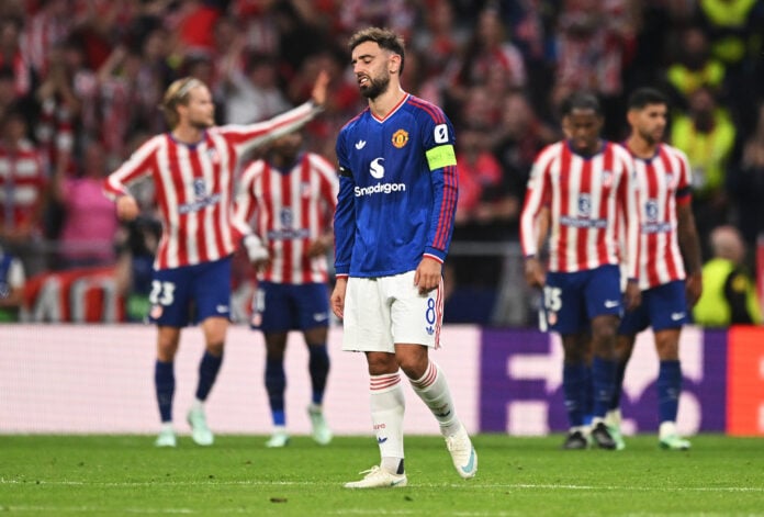 Manchester United captain Bruno Fernandes walks with his head down as Atletico Madrid players celebrate behind him