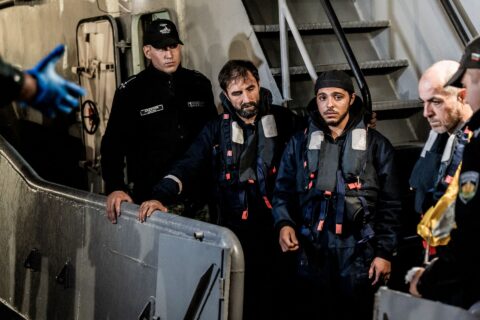 Rescued sailors in life jackets stand beside Bulgarian navy personnel after arriving at the port of Varna