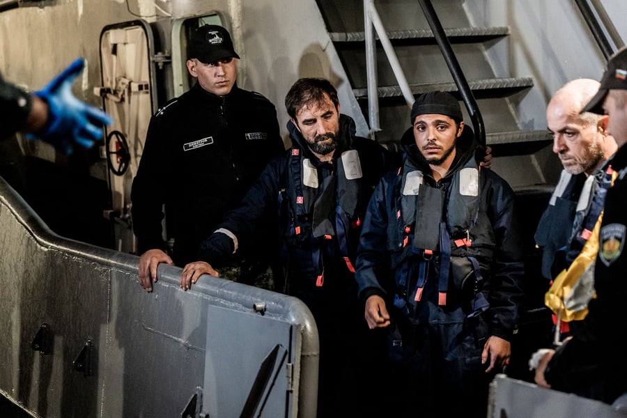 Rescued sailors in life jackets stand beside Bulgarian navy personnel after arriving at the port of Varna