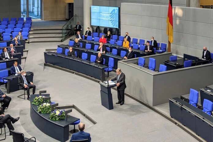 The plenary chamber of the German Bundestag in Berlin, with a speaker at the lectern and politicians seated in blue chairs