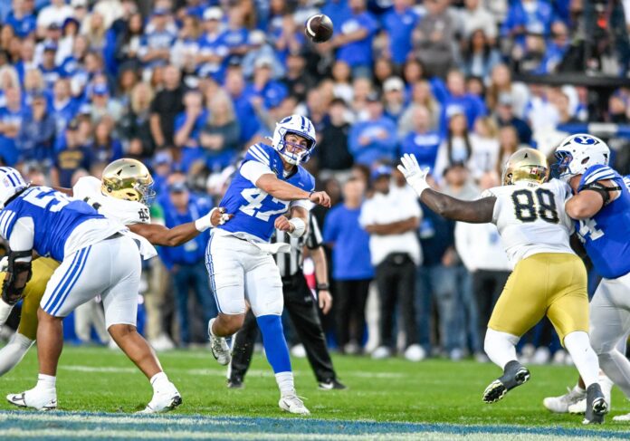 BYU quarterback Bear Bachmeier in a No. 47 blue jersey throws a pass as Notre Dame defenders close in at LaVell Edwards Stadium