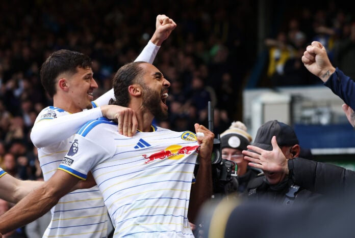Leeds United striker Dominic Calvert-Lewin roars and tugs his shirt as team-mates celebrate his equaliser against Manchester United at Elland Road